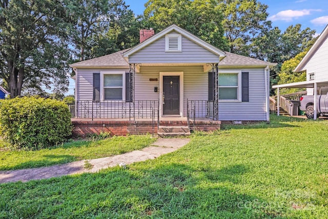 2405 Greenland Ave, Charlotte, NC 28208 - bungalow-style home featuring a chimney, a shingled roof, covered porch, and a front lawn