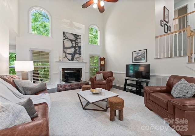9141 Covey Hollow Ct, Charlotte, NC 28210 - living room featuring a high ceiling, ceiling fan, healthy amount of natural light, a brick fireplace, and wainscoting