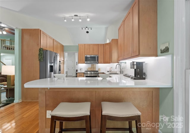 9141 Covey Hollow Ct, Charlotte, NC 28210 - kitchen with stainless steel appliances, a peninsula, light countertops, light wood finished floors, and a breakfast bar