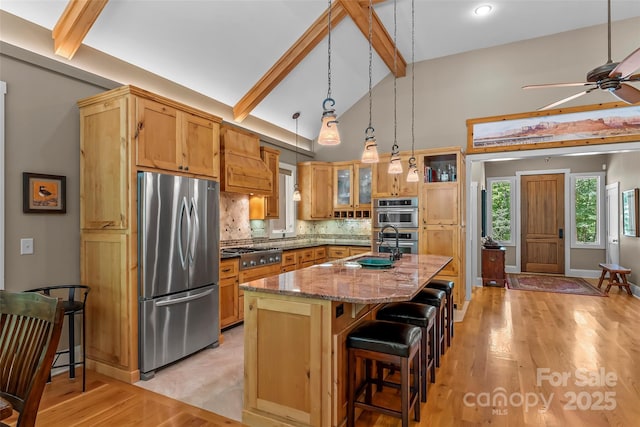 429 Turtle Head Dr, Nebo, NC 28761 - kitchen with stainless steel appliances, beam ceiling, a kitchen bar, tasteful backsplash, and light wood-type flooring