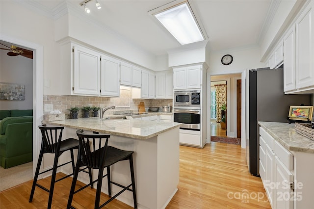 5008 Saddle Horn Trl, Weddington, NC 28104 - kitchen with stainless steel appliances, a peninsula, tasteful backsplash, white cabinets, and crown molding