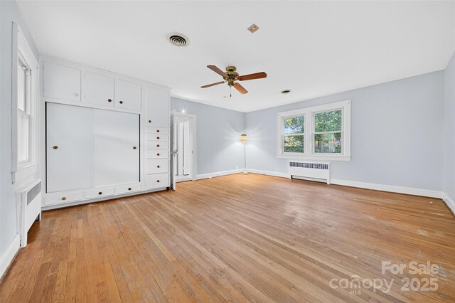 422 Wagner St, Troutman, NC 28166 - unfurnished bedroom with radiator heating unit, light wood-style flooring, and a ceiling fan