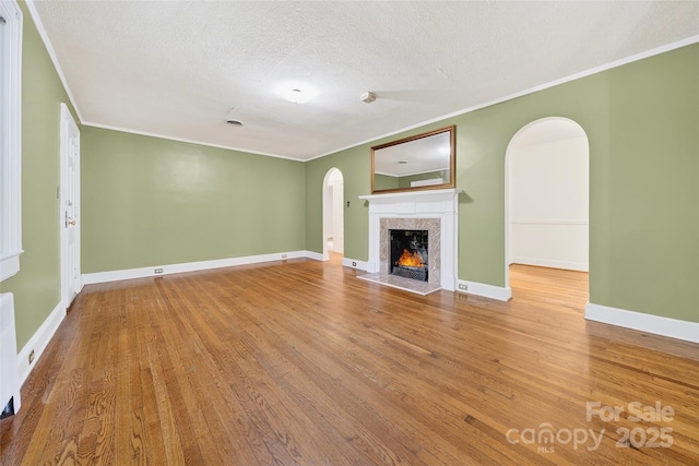 422 Wagner St, Troutman, NC 28166 - unfurnished living room with arched walkways, ornamental molding, wood finished floors, a high end fireplace, and a textured ceiling