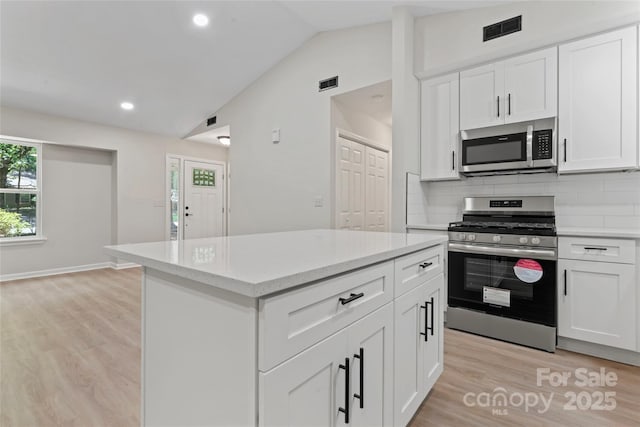 5534 Great Wagon Rd, Charlotte, NC 28215 - kitchen featuring stainless steel appliances, vaulted ceiling, light wood finished floors, backsplash, and white cabinetry