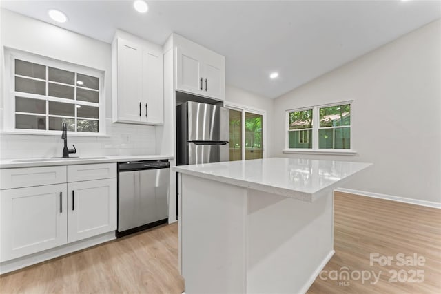 5534 Great Wagon Rd, Charlotte, NC 28215 - kitchen featuring stainless steel appliances, tasteful backsplash, white cabinetry, light wood-type flooring, and lofted ceiling