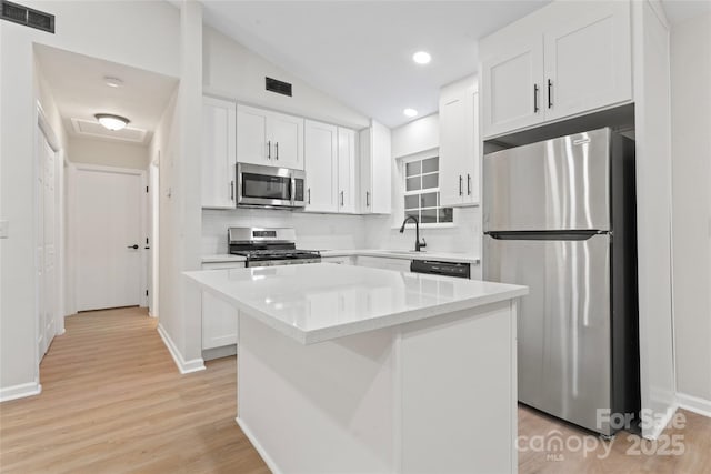 5534 Great Wagon Rd, Charlotte, NC 28215 - kitchen with appliances with stainless steel finishes, tasteful backsplash, white cabinetry, a kitchen island, and lofted ceiling