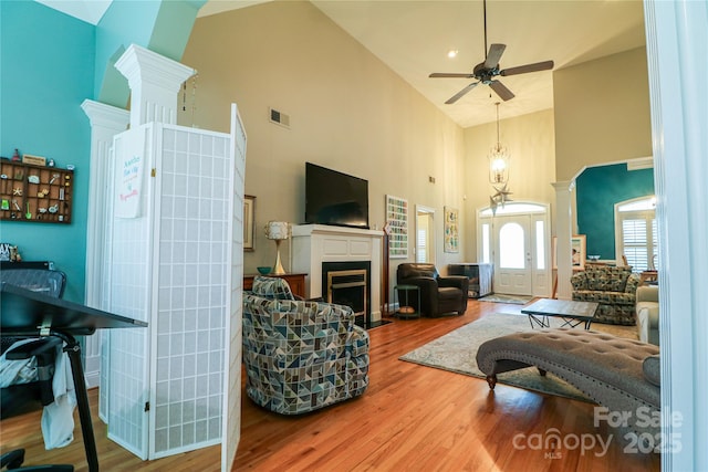 406 Spyglass Hill Pl, Salisbury, NC 28144 - living area with a high ceiling, wood finished floors, a ceiling fan, a fireplace with flush hearth, and decorative columns
