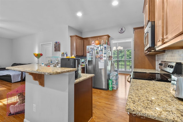 2953 Cameron Village Ct, Winston Salem, NC 27103 - kitchen featuring stainless steel appliances, a peninsula, light wood finished floors, backsplash, and a kitchen bar