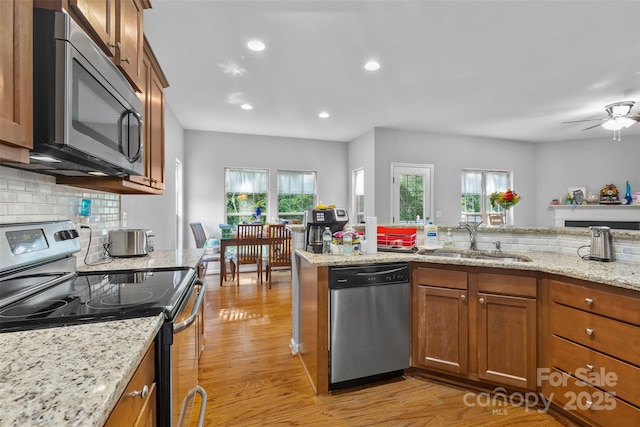 2953 Cameron Village Ct, Winston Salem, NC 27103 - kitchen with stainless steel appliances, brown cabinetry, light wood-style floors, plenty of natural light, and recessed lighting