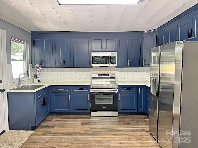 201 Barnes Ln, Stony Point, NC 28678 - kitchen featuring stainless steel appliances, blue cabinets, wood finished floors, and light countertops