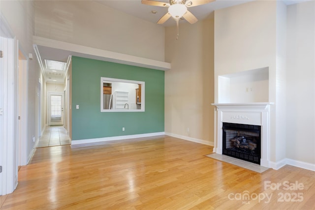 2785 Clover Rd NW, Concord, NC 28027 - unfurnished living room with a fireplace with flush hearth, light wood-type flooring, ceiling fan, and a towering ceiling