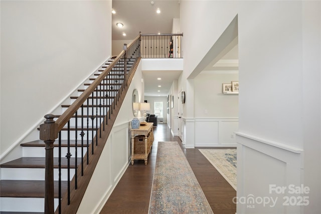 13339 Mcguffy Dr, Huntersville, NC 28078 - staircase featuring wood finished floors, a high ceiling, a decorative wall, a wainscoted wall, and recessed lighting