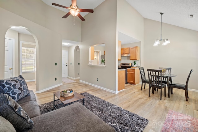 121 Gilcrest Ln, Troutman, NC 28166 - living area with arched walkways, a ceiling fan, light wood-type flooring, high vaulted ceiling, and a chandelier
