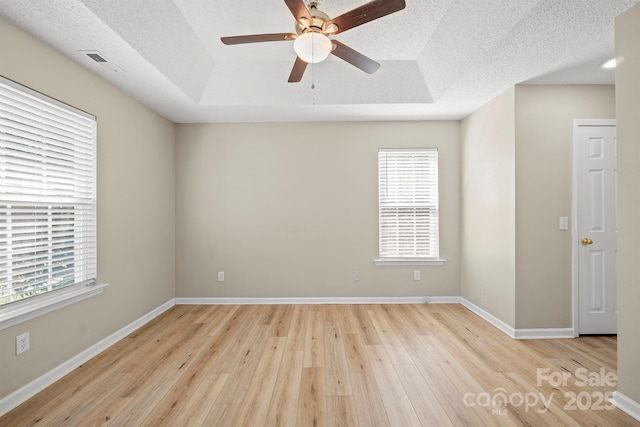 121 Gilcrest Ln, Troutman, NC 28166 - spare room with light wood-style flooring, plenty of natural light, ceiling fan, a tray ceiling, and a textured ceiling