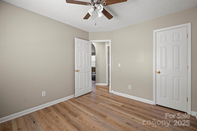 121 Gilcrest Ln, Troutman, NC 28166 - unfurnished bedroom featuring light wood-style flooring, arched walkways, a textured ceiling, and a ceiling fan