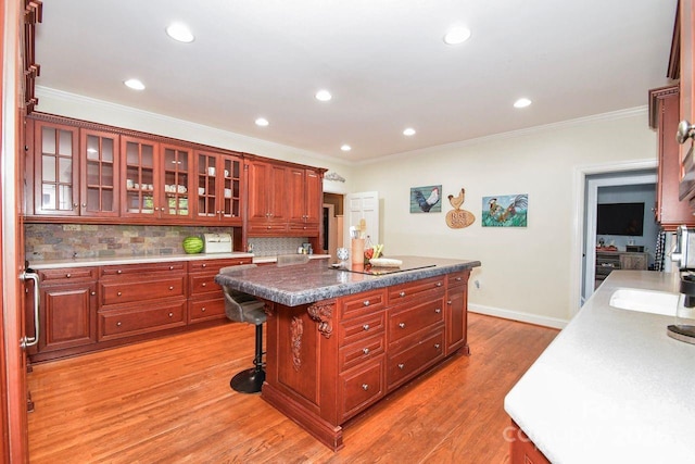711 Yadkin St, Albemarle, NC 28001 - kitchen with light wood-style floors, crown molding, a kitchen island, tasteful backsplash, and glass insert cabinets