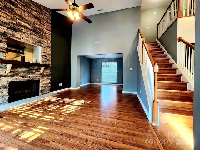 3108 Leicester Dr, Matthews, NC 28104 - unfurnished living room featuring wood finished floors, a ceiling fan, a towering ceiling, stairs, and a fireplace