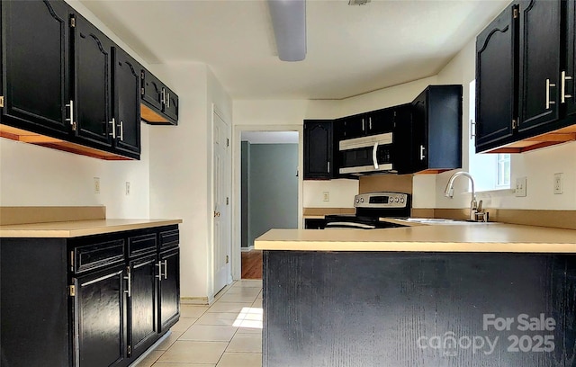 3108 Leicester Dr, Matthews, NC 28104 - kitchen featuring dark cabinets, stainless steel appliances, light tile patterned flooring, and a peninsula