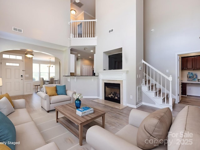 621 Pine Links Dr, Tega Cay, SC 29708 - living room featuring light wood-style floors, stairway, arched walkways, a towering ceiling, and a high end fireplace