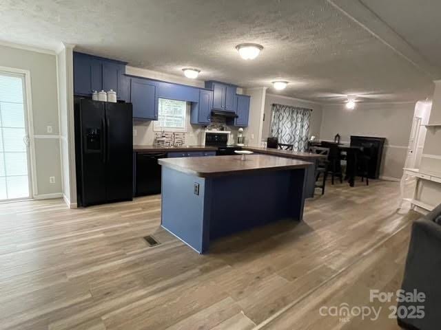25 Mountain View Rdg, Fairview, NC 28730 - kitchen with black appliances, blue cabinets, a textured ceiling, dark countertops, and a center island