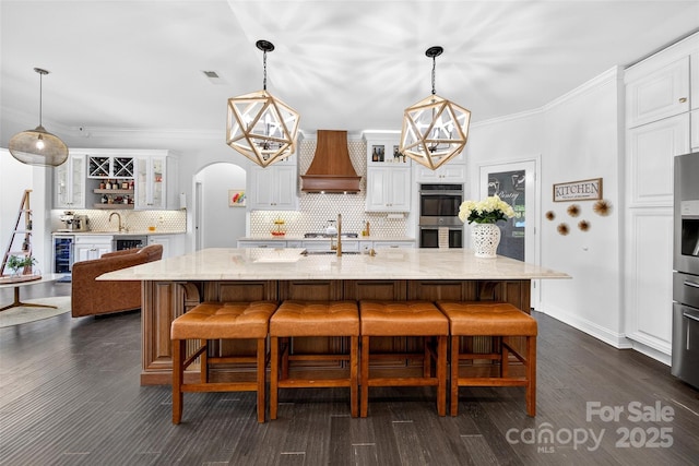 3981 Spinnaker Pl, Denver, NC 28037 - kitchen with custom exhaust hood, beverage cooler, arched walkways, decorative backsplash, and glass insert cabinets
