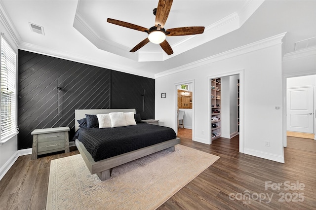 3981 Spinnaker Pl, Denver, NC 28037 - bedroom with a walk in closet, an accent wall, wood finished floors, crown molding, and a raised ceiling
