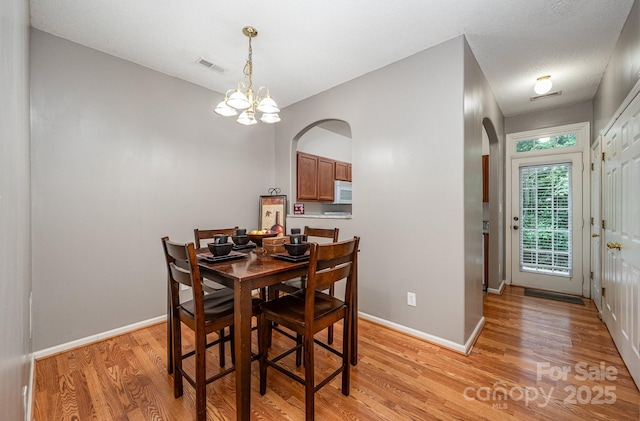 7518 Silver Arrow Dr, Charlotte, NC 28273 - dining area with arched walkways, light wood finished floors, and a chandelier