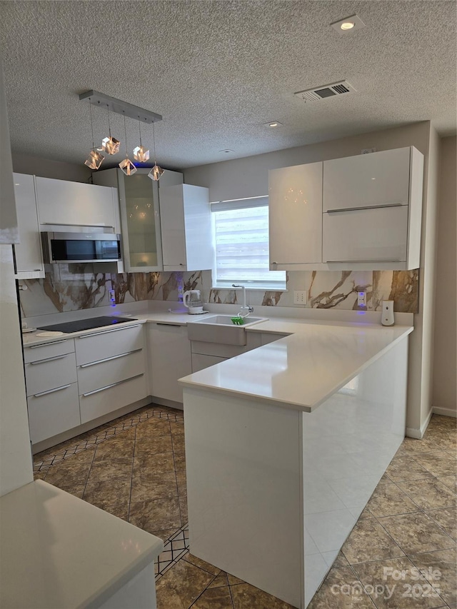 3 Hidden Sands Ct, Columbia, SC 29229 - kitchen featuring stainless steel microwave, a peninsula, white cabinetry, decorative backsplash, and modern cabinets