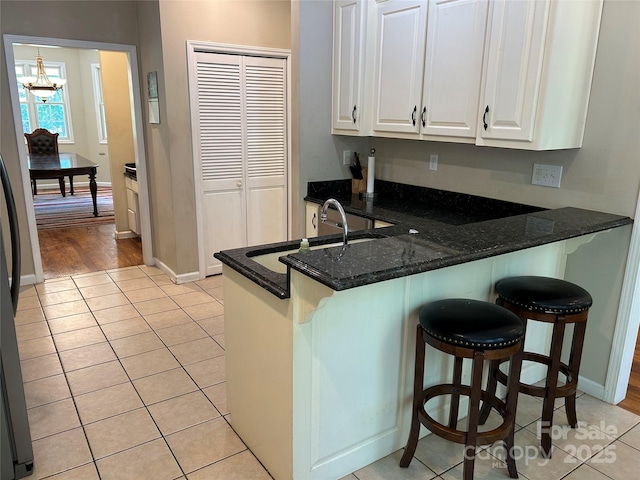 207 Wagon Ln, Rutherfordton, NC 28139 - kitchen with white cabinetry, light tile patterned floors, a peninsula, dark stone counters, and a breakfast bar