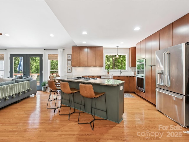 1711 Apple Tree Ln Unit 28, Fort Mill, SC 29715 - kitchen featuring appliances with stainless steel finishes, a kitchen breakfast bar, open floor plan, light wood-style flooring, and light stone counters