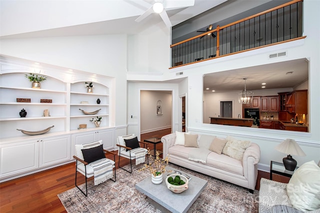 7554 Bluestar Ln, Charlotte, NC 28226 - living room featuring a towering ceiling, wood finished floors, a ceiling fan, a chandelier, and built in shelves