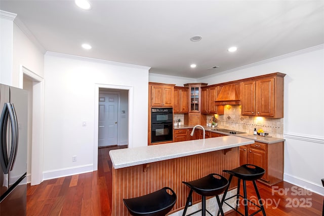7554 Bluestar Ln, Charlotte, NC 28226 - kitchen with black appliances, custom range hood, brown cabinetry, backsplash, and dark wood-type flooring