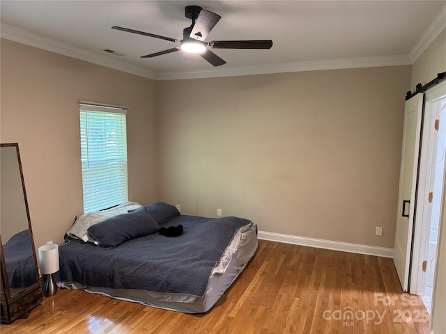 13221 Brandywine Ln, Midland, NC 28107 - bedroom with wood finished floors, a barn door, ornamental molding, and a ceiling fan