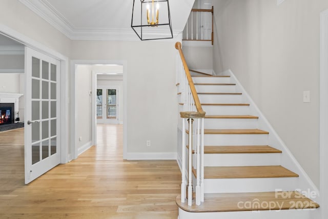 1134 Willow Oaks Trl, Matthews, NC 28104 - stairway featuring a chandelier, wood finished floors, crown molding, and a warm lit fireplace