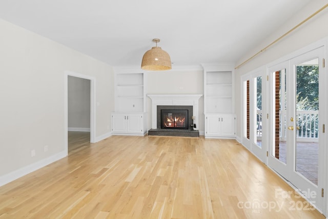 1134 Willow Oaks Trl, Matthews, NC 28104 - unfurnished living room featuring built in features, light wood-style flooring, and a glass covered fireplace