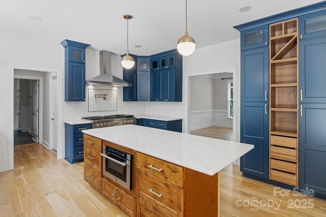 1134 Willow Oaks Trl, Matthews, NC 28104 - kitchen featuring wall chimney range hood, light wood-style flooring, stainless steel gas stovetop, and blue cabinetry