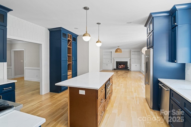1134 Willow Oaks Trl, Matthews, NC 28104 - kitchen featuring stainless steel appliances, open floor plan, blue cabinets, light wood finished floors, and wainscoting