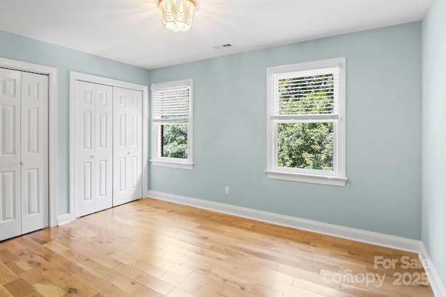 1134 Willow Oaks Trl, Matthews, NC 28104 - unfurnished bedroom with multiple windows, multiple closets, and light wood-type flooring