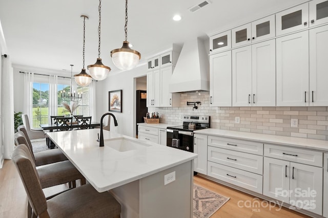 19 Berea Baptist Church Rd, Stanfield, NC 28163 - kitchen featuring custom exhaust hood, electric stove, a kitchen bar, an island with sink, and decorative backsplash