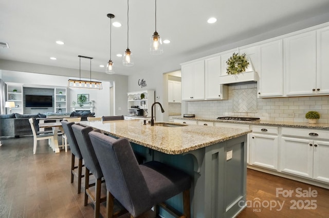 5105 Paisano Ln, Waxhaw, NC 28173 - kitchen featuring stainless steel gas stovetop, backsplash, open floor plan, light stone countertops, and an island with sink