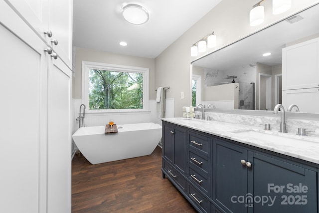 5408 Apple Glen Dr, Harrisburg, NC 28075 - bathroom with double vanity, wood finished floors, a stall shower, a freestanding tub, and wainscoting