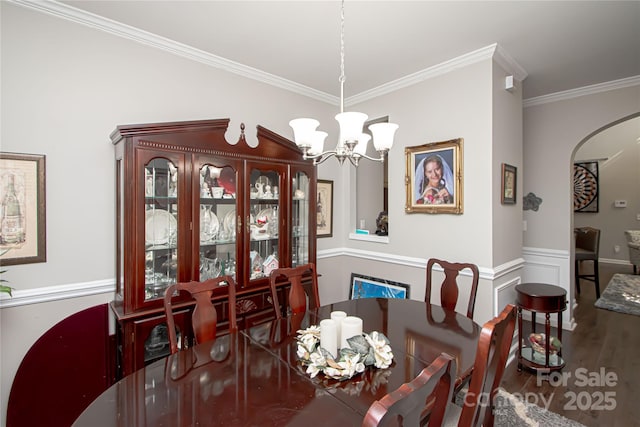 1304 Hammond Dr, Matthews, NC 28104 - dining space with a chandelier, crown molding, wood finished floors, arched walkways, and a wainscoted wall