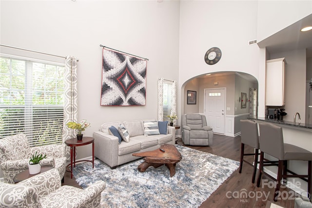1304 Hammond Dr, Matthews, NC 28104 - living room featuring arched walkways, a high ceiling, and dark wood finished floors