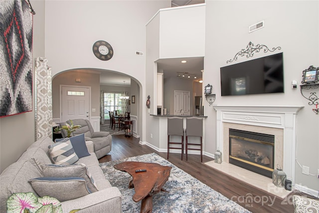 1304 Hammond Dr, Matthews, NC 28104 - living area with arched walkways, dark wood finished floors, a towering ceiling, and a fireplace