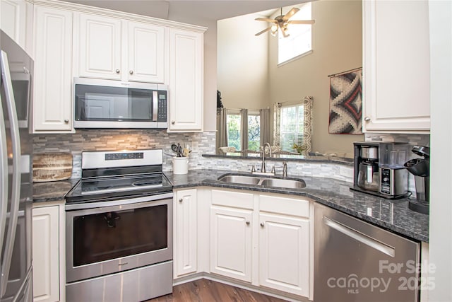 1304 Hammond Dr, Matthews, NC 28104 - kitchen featuring appliances with stainless steel finishes, a ceiling fan, tasteful backsplash, white cabinets, and a high ceiling