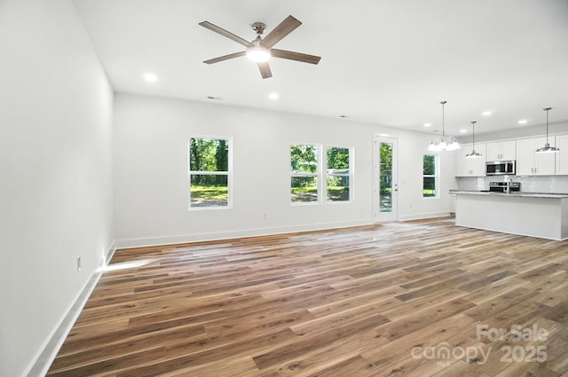 411 Patience Dr, Concord, NC 28025 - unfurnished living room with plenty of natural light, light wood-style flooring, recessed lighting, a chandelier, and a ceiling fan