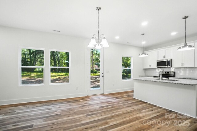411 Patience Dr, Concord, NC 28025 - kitchen featuring stainless steel microwave, white cabinetry, tasteful backsplash, light wood-type flooring, and light stone countertops