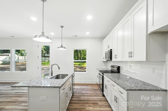 411 Patience Dr, Concord, NC 28025 - kitchen with appliances with stainless steel finishes, recessed lighting, wood finished floors, a kitchen island with sink, and backsplash