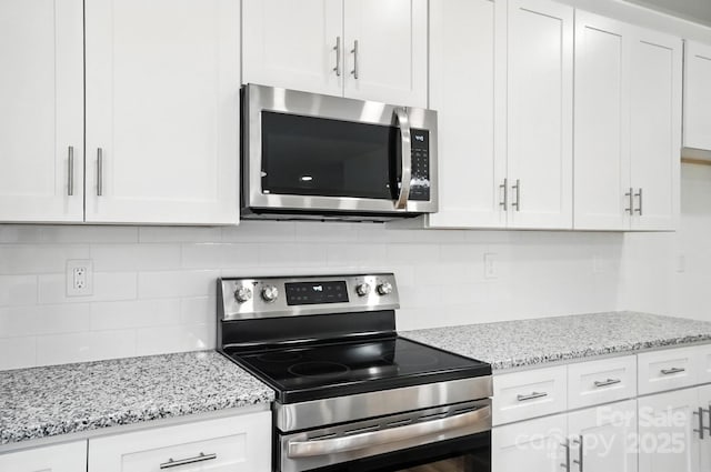 411 Patience Dr, Concord, NC 28025 - kitchen with appliances with stainless steel finishes, white cabinetry, decorative backsplash, and light stone counters
