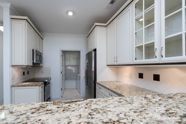 18730 Nautical Dr Unit 102, Cornelius, NC 28031 - kitchen featuring appliances with stainless steel finishes, tasteful backsplash, glass insert cabinets, ornamental molding, and light stone counters